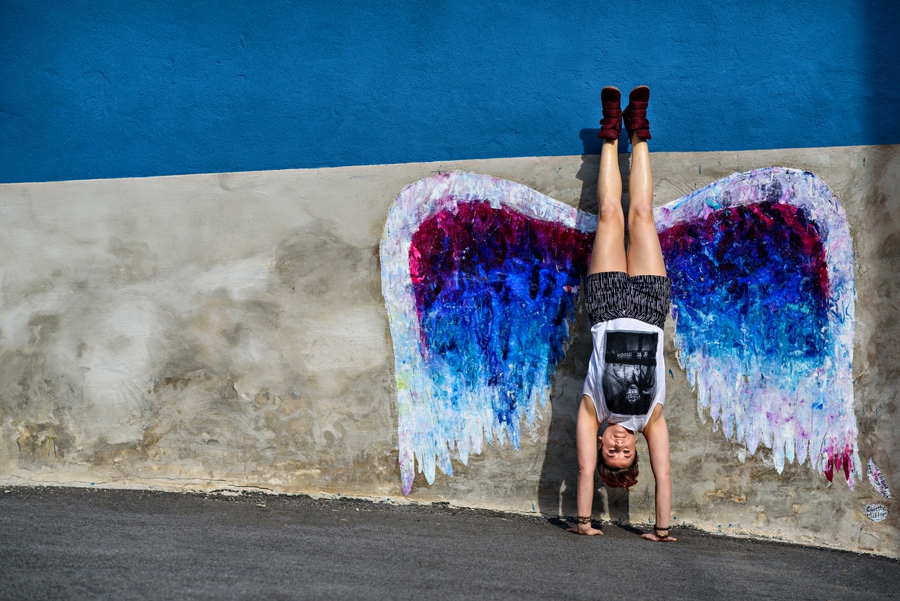 A woman doing a handstand in front of angel wings in philadelphia.